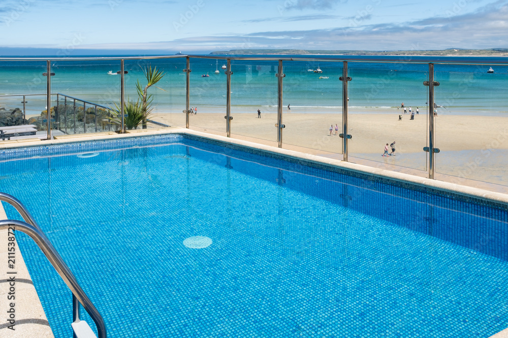 A vibrant blue hotel swimming pool at the edge of Porthminster Beach, St Ives.