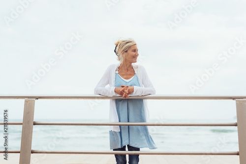 Slender trendy blond woman on a waterfront pier photo