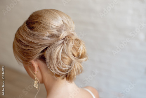 Rear view of female hairstyle middle bun with blond hair.