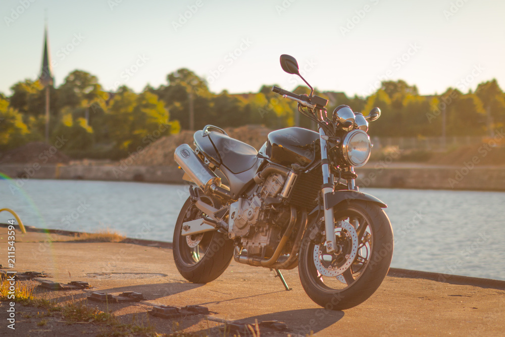 Obraz premium Motocykl na wodzie o zachodzie słońca