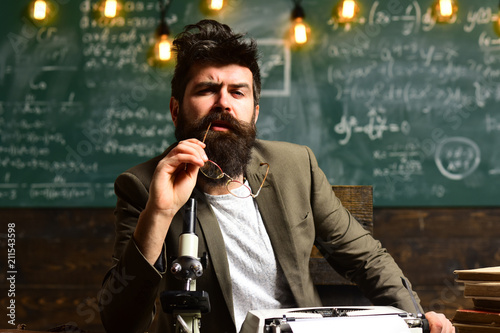 Man with beard on thinking face. Bearded man with retro typewriter and microscope. Scientist make research in university. Businessman with glasses sit at desk. Research or knowledge and innovation