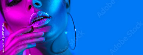 High fashion model woman in colorful bright neon lights posing in studio. Beautiful sexy girl, trendy glowing makeup, metallic silver lips photo