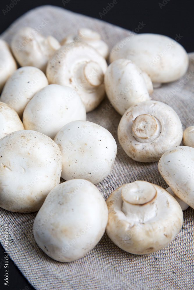 Fresh raw champignon mushrooms, side view. Close-up. Black background.