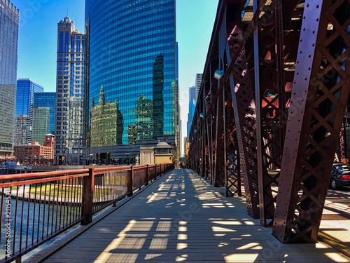 Chicago's elevated train tracks cast shadows on Lake Street and sidewalk along the river in downtown Loop. photo
