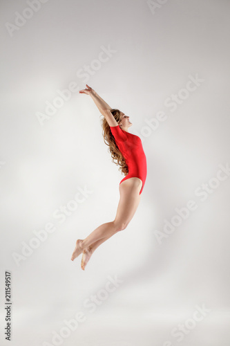 beautiful gymnast in red leotard jumping isolated on white background