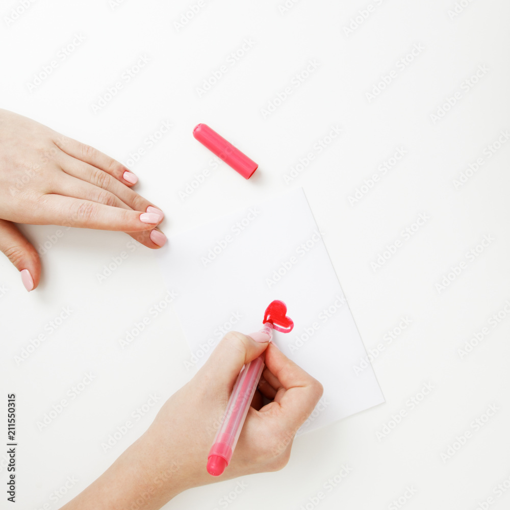 Flat lay. Top view. Hand of girl writing love letter on Saint Valentines Day. Handmade postcard with red heart shaped figure. Woman write Love on postcard for 14 February holiday celebration Flat lay. Top view. Hand of girl writing love letter on Saint Valentines Day. Handmade postcard with red heart shaped figure. Woman write Love on postcard for 14 February holiday celebration