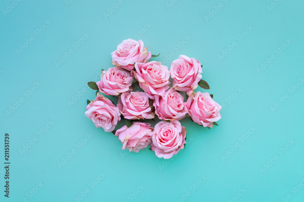 Several satin pink rose buds on turquoise pastel background. Top view. Several satin pink rose buds on turquoise pastel background. Top view.