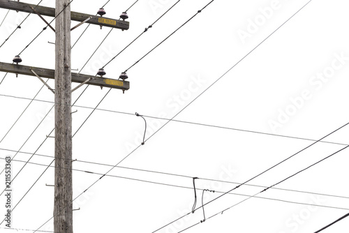 Power poles and crossed electrical distribution wire silhouetted against a light grey sky. 