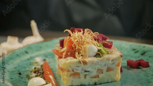 Russian traditional cuisine. Shub salad with herring. Dolly shot. On a black wooden background. Copy space. photo