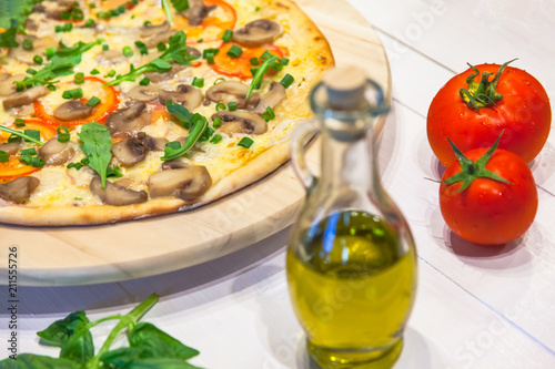 appetizing vegetarian pizza with olive oil on a white table