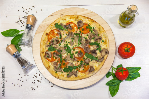 appetizing vegetarian pizza with olive oil, spices and basil leaves on a white table, flat lay