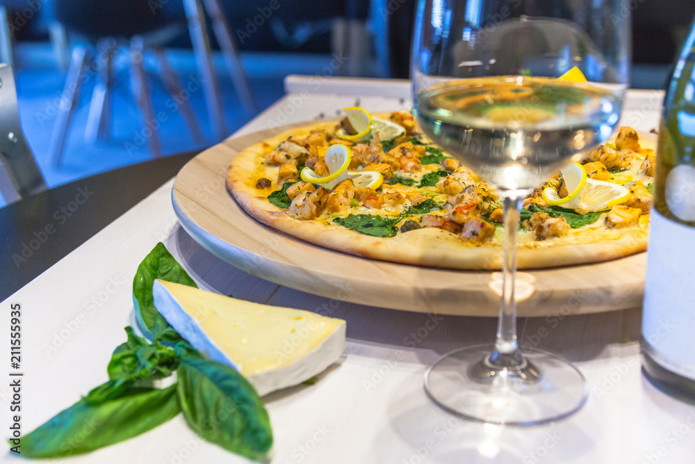 appetizing pizza with shrimps, lemon and a glass of wine on a white table appetizing pizza with shrimps, lemon and a glass of wine on a white table