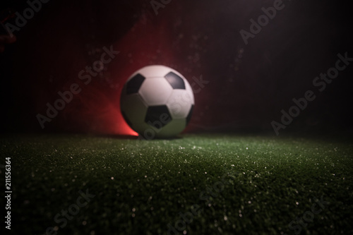 Traditional soccer ball on soccer field. Close up view of soccer ball (football) on green grass with dark toned foggy background. © zef art