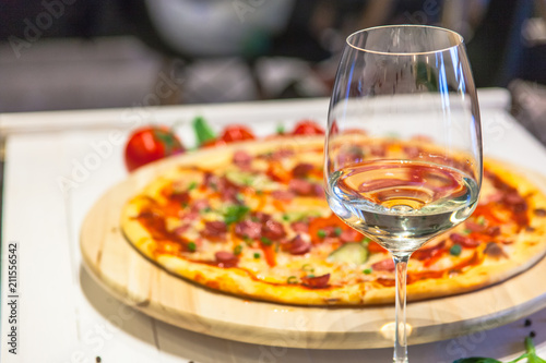 a glass of white wine on a background of delicious pizza