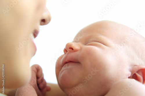 mom looks at a smiling sleeping newborn baby close-up