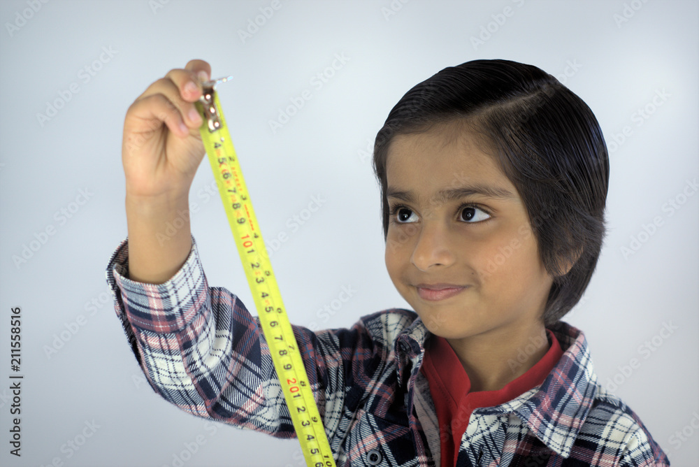 Kid with measuring tape. Smiling kid looking at numbers on tape measure.  Concept of measuring height or growing tall Stock Photo