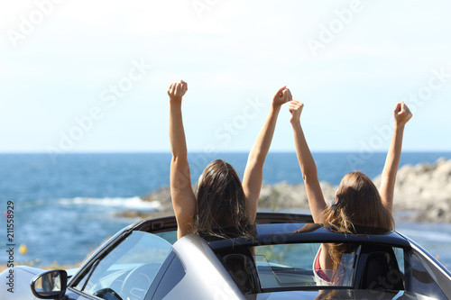 Joyful tourists watching the sea in a convertible car