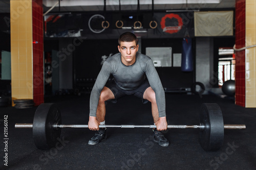 A man raises in the gym bar, the athlete trains, bodybuilding