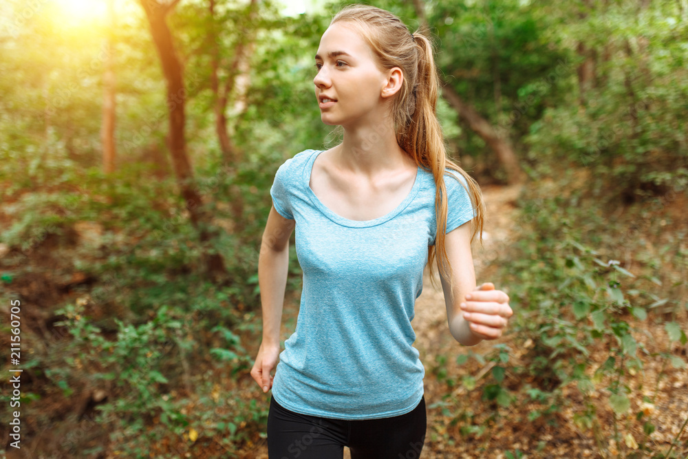 Beautiful girl running through the woods, morning jog, athlete Beautiful girl running through the woods, morning jog, athlete