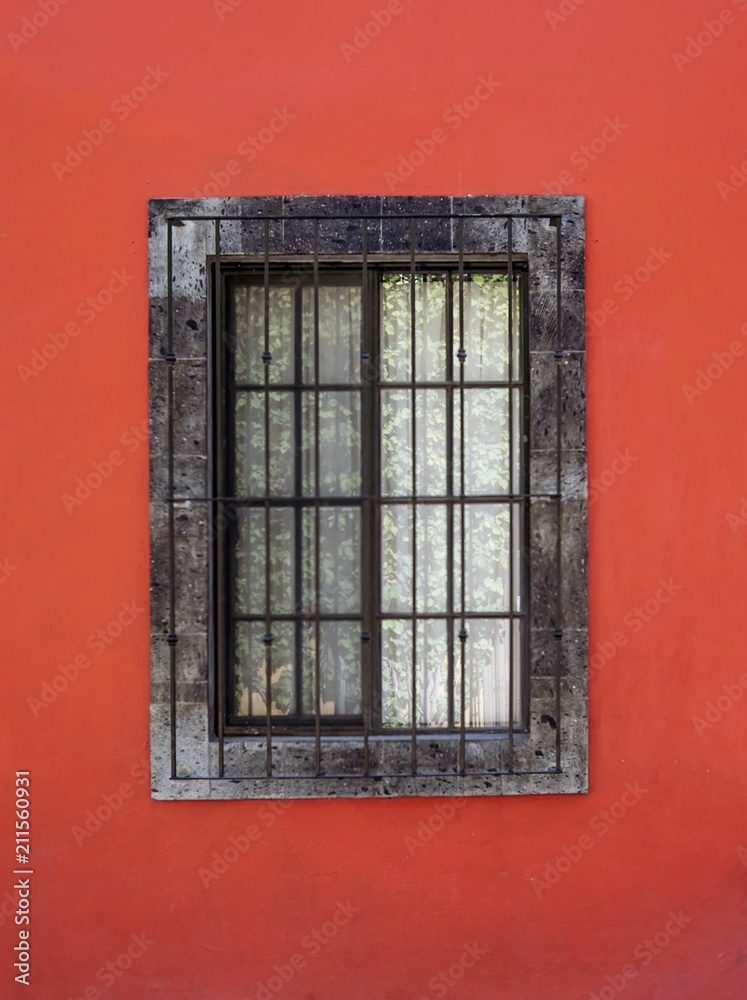 Obraz premium Isolated window on bright red stucco wall in Mexico 