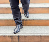 Businessman legs taking step on a lower level on a stairs - bad business investment decision concept