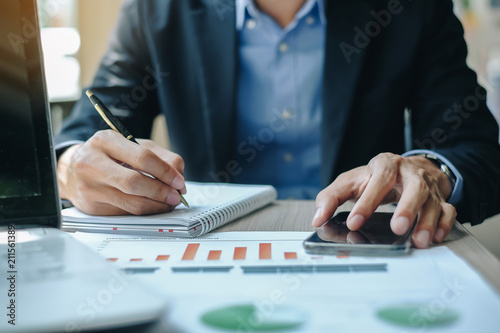 Businessman using smatphone for analysis maketing plan, Manager calculate financial report and graph chart.  Business, Finance and Accounting concepts
