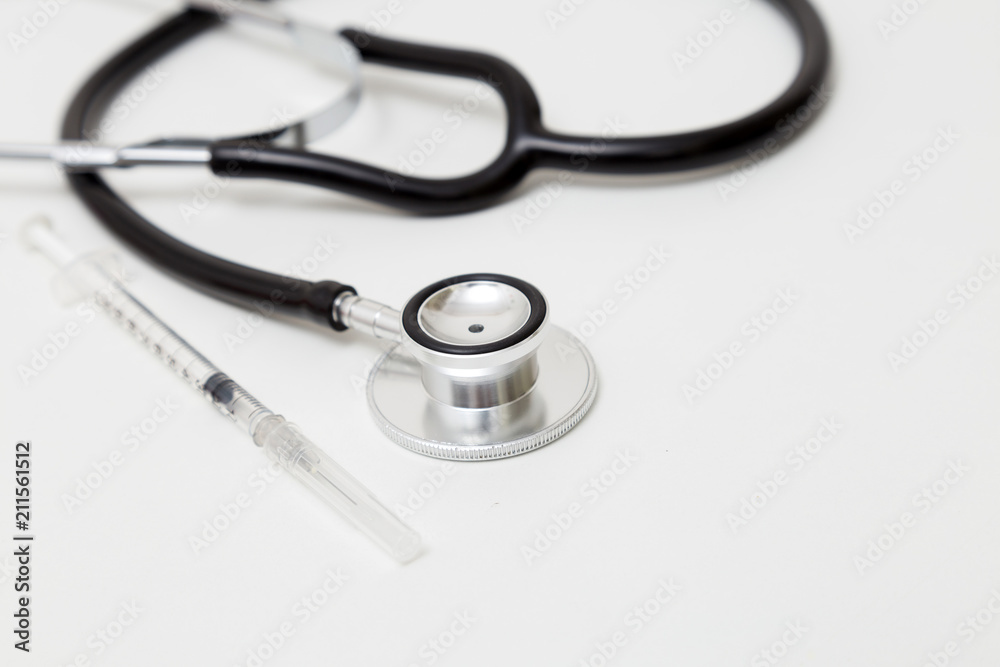 Stethoscope and syringe on table. Isolated on white background. Studio lighting. Concept for healthy and medical Stethoscope and syringe on table. Isolated on white background. Studio lighting. Concept for healthy and medical
