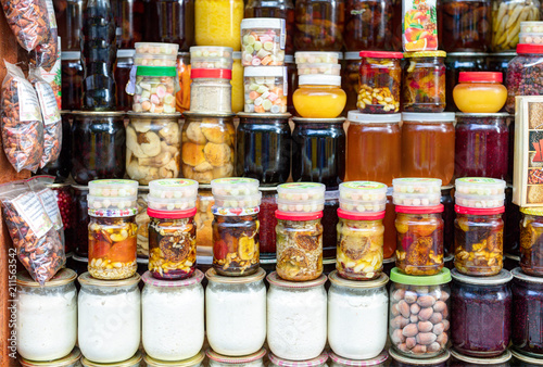 Various canned vegetables, nuts, and mushrooms in the glass jars.