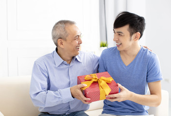 happy family celebrating and son giving gift to father