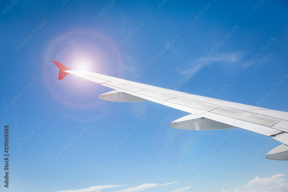 Fototapeta premium Wing of the plane on blue sky with sunlight. travel concept