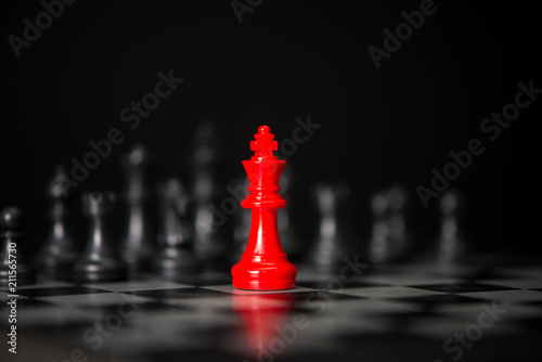 Red chess between black chess board game for competition and strategy, business success concept