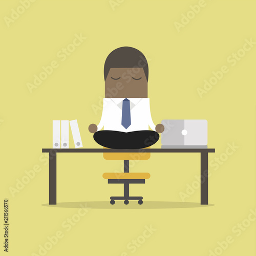 African businessman meditation in office. yoga at job. young man relaxing in lotus position on table with computer at work.