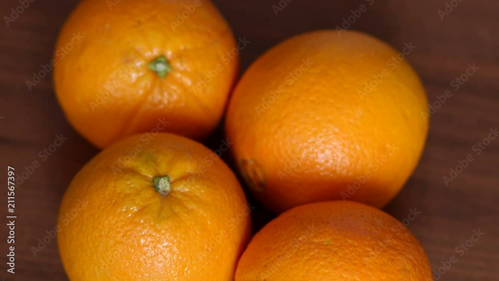 Four ripe juicy oranges on a brown wooden surface. Close-up. High resolution. Four ripe juicy oranges on a brown wooden surface. Close-up. High resolution.