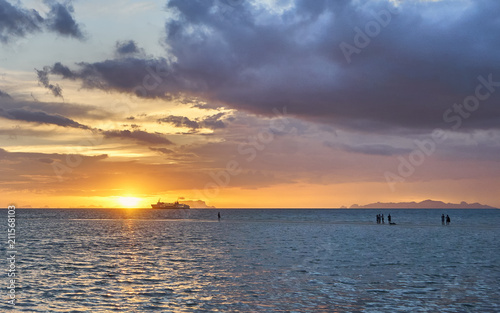 People are looking at the spectacular sunset and ship in the sea
