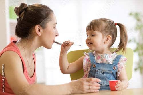 playful child girl spoon feeding her mother