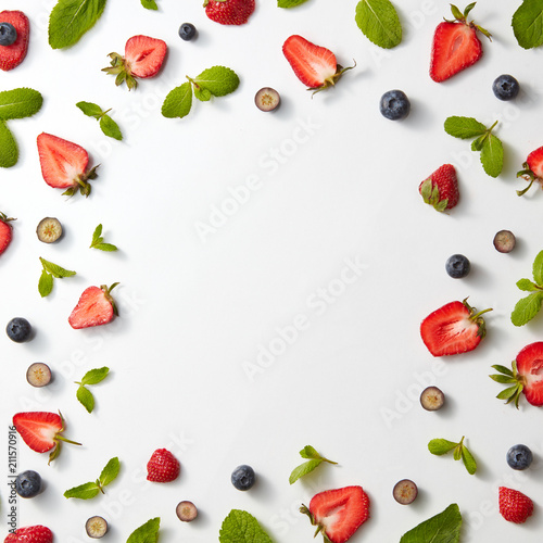 Fototapeta Naklejka Na Ścianę i Meble -  A pattern of strawberries and blueberries with mint on a gray background. Berry frame. Flat lay