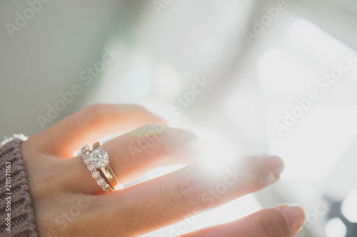 Close up of elegant diamond ring on woman finger with dark pink sweater winter clothe and sunlight tone. love and wedding concept.soft and selective focus. photo