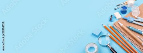 School stationary on blue background. Notebook, pens, pencils and other tools. Banner for website. photo