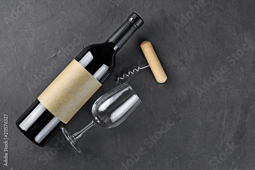 Flat lay of lying red wine bottle with empty label, corkscrew and glass for tasting