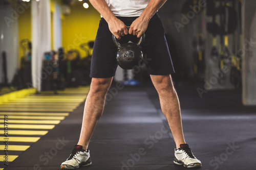 Close up male arms holding hard kettlebell while exercising in keep-fit studio