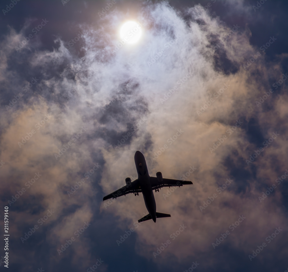 The plane flies in the sky against the sun.
The plane flies in the sky against the sun.