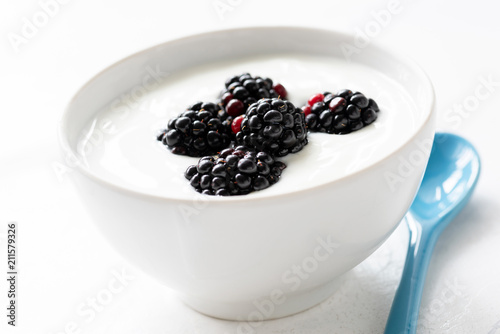 Yogurt with blackberries in a bowl. Isolated on white. Healthy eating concept