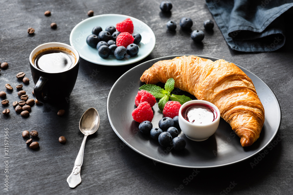 French breakfast with croissant, berries, jam and black coffee