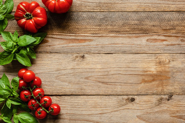 Tomatoes and basil on wood background, cooking ingredients. Food background, pizza or picnic background with copy space for text