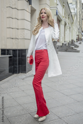Fashionable young blonde in a spring fashionable suit and with a shopping bag in the center of Moscow
