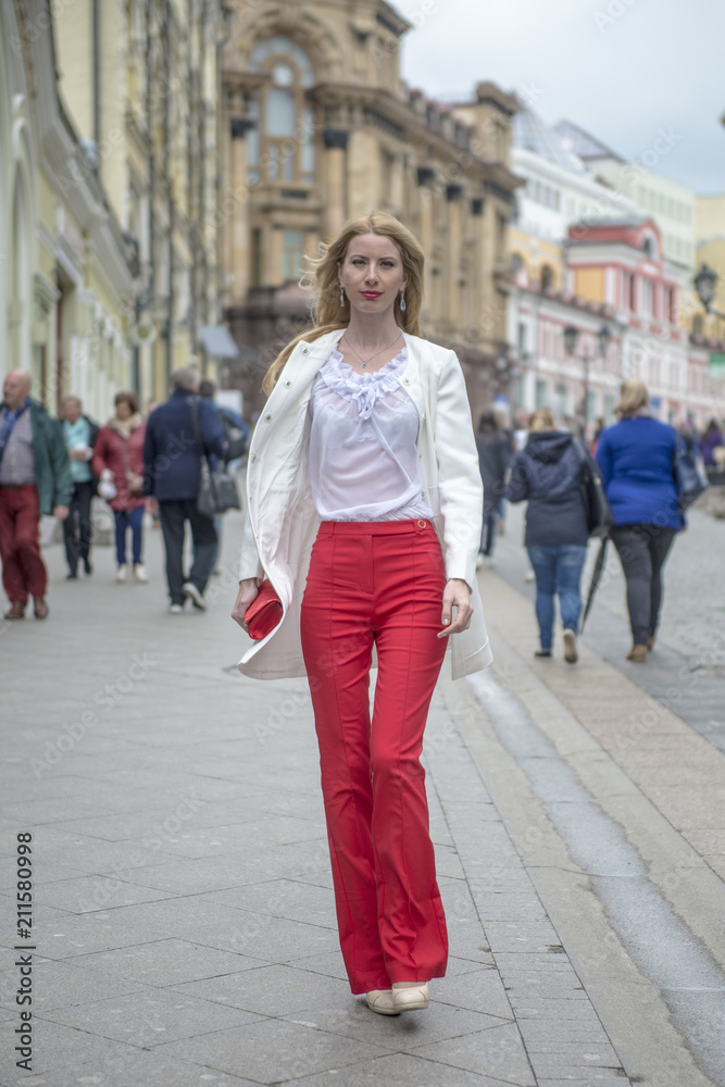 Fashionable young blonde in a spring fashionable suit and with a shopping bag in the center of Moscow
