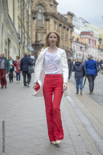 Fashionable young blonde in a spring fashionable suit and with a shopping bag in the center of Moscow
