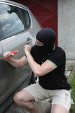Car thief trying to break into a car with a screwdriver.