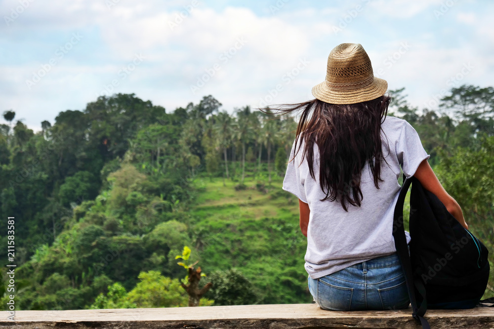 A woman sitting on a wooden bench admires the fantastic landscape in front of her and the nature that surrounds her after a big walk. Concept of adventure, vacation and travel.