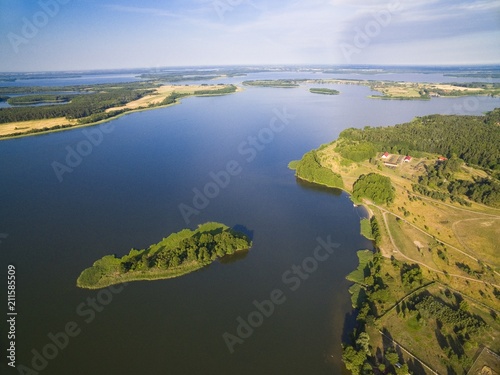 Aerial view of small uninhabited island on lake with sky reflected in calm water, Swiecajty Lake, Mazury, Poland